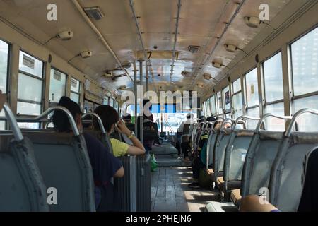 BANGKOK/THAILANDIA - 25 febbraio 2023: Passeggeri seduti all'interno dell'autobus scoperto a Bangkok, le persone utilizzano i mezzi pubblici per lavorare. Foto Stock