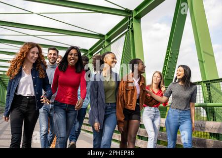 Grande gruppo di persone della generazione Z, giovani studenti universitari a piedi e divertirsi all'aperto in un luogo urbano Foto Stock