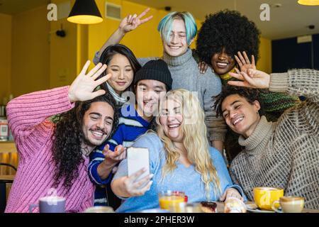 Giovane donna curvy scatta una foto con i suoi migliori amici durante una colazione in caffè, multirazziale e inclusivo gruppo diversità, concentrarsi sul volto asiatico ragazzo Foto Stock