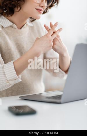 Vista ritagliata dell'insegnante che mostra l'alfabeto britannico a due mani che significa lettera f mentre insegna il fingerspelling online, immagine stock Foto Stock