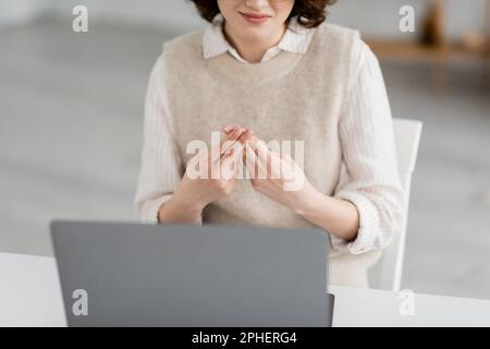 Vista parziale dell'insegnante sorridente che mostra l'alfabeto britannico a due mani durante la lezione online, immagine di scorta Foto Stock