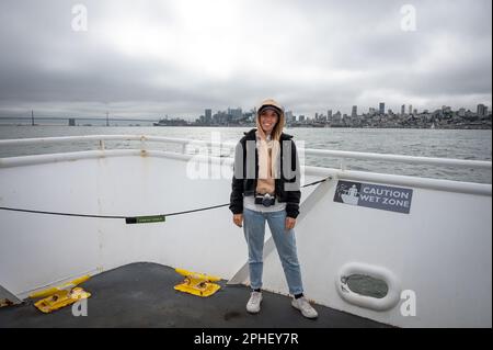 Ritratto di una giovane ragazza in giacca e cappuccio che naviga sul mare nella città di San Francisco Foto Stock