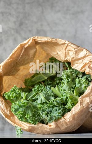 Kale in un sacchetto di carta marrone. Concetto di imballaggio ecologico sostenibile e biodegradabile privo di plastica Foto Stock