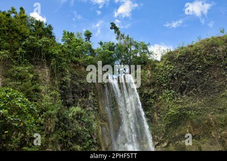 L'idilliaca cascata di Camugao a Siquijor nelle Filippine circondata dalla foresta pluviale illuminata dalla luce. Foto Stock