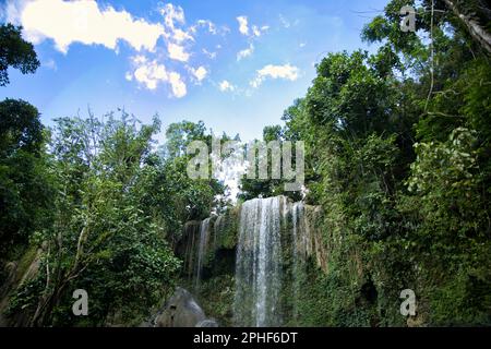 L'idilliaca cascata di Camugao a Siquijor nelle Filippine circondata dalla foresta pluviale illuminata dalla luce. Foto Stock