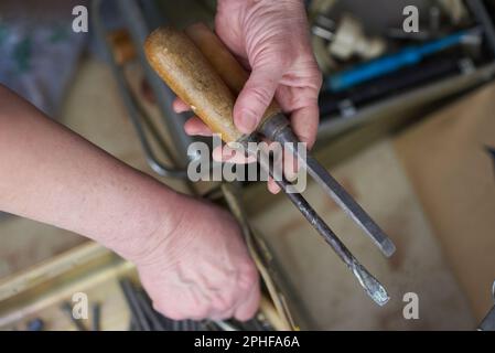 Il padrone tiene in mano un set di attrezzi: Uno scalpello e un cacciavite con manici in legno Foto Stock