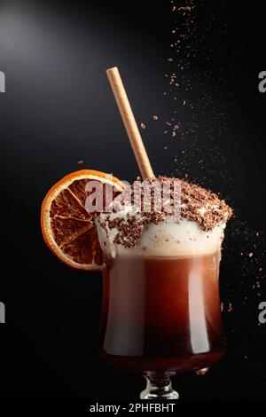 Cocktail al cioccolato con panna montata cosparsa di gocce di cioccolato e guarnita con una fetta di arancia secca. Spazio di copia. Foto Stock
