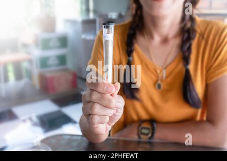 Una sigaretta unita alla marijuana in un primo piano di un pacchetto in mano a una donna. Vendita di cannabis medica. Foto Stock