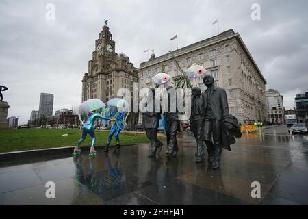 Al lancio dell'Eurovision EuroFestival di Liverpool, gli artisti che si vestono come meduse sui pattini a rotelle pattinano intorno alla statua dei Beatles. Il festival di due settimane, che consisterà in 25 commissioni - 19 delle quali sono collaborazioni tra artisti britannici e ucraini - prenderà il controllo della città in testa fino al Concorso di canzoni Eurovision mentre i fan di tutto il mondo scenderanno a Liverpool. Data immagine: Martedì 28 marzo 2023. Foto Stock