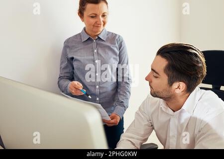 Colleghi aziendali che discutono di dati finanziari che lavorano insieme in ufficio. Persone imprenditori che lavorano con grafici e tabelle sul computer. Due persone Foto Stock