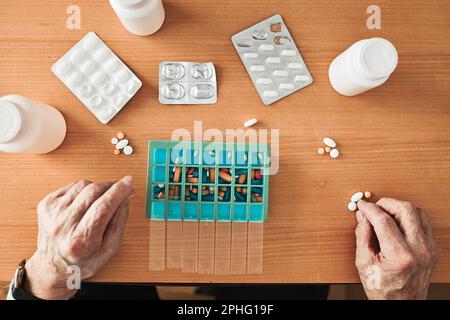 Uomo anziano che organizza il suo farmaco in un dispenser di pillole. Uomo anziano che prende le pillole dalla scatola. Assistenza sanitaria e concetto di vecchiaia con farmaci. Medicamenti Foto Stock