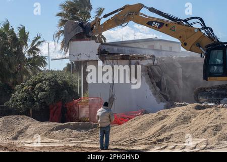 Corigliano Rossano, Italia. 28th Mar, 2023. I bulldozer demoliscono il lido delle Sirene a Corigliano Rossano a seguito di un'ordinanza del comune. Questa struttura era illegale e sulla spiaggia, su terreni di proprietà statale. Era stata abbandonata e fatiscente per molti anni ed è stata considerata un eco-mostro in concreto. In passato era una discoteca della 'Ndrangheta e per anni gestita dalla mafia. Credit: Independent Photo Agency/Alamy Live News Foto Stock