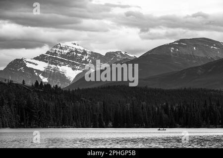 Lago Beauvert in bianco e nero con persone in kayak e Monte Edith Cavell, parco nazionale di Jasper, Canada. Foto Stock