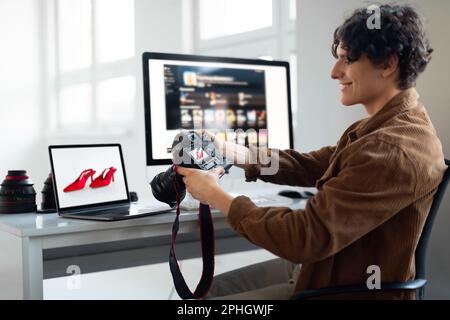 Giovane fotografo, guarda foto e video sulla fotocamera, trasferendo le foto sul laptop per ritoccare Foto Stock