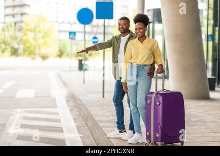 Happy Black turisti coppia Taxi Hailing fermata taxi in piedi all'esterno Foto Stock