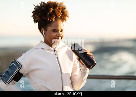 Donna nera sportiva felice in Activewear relax dopo allenamento fitness all'aperto Foto Stock