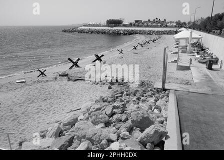 Odessa, Ucraina -2022: Barriere militari metalliche, ricci anticarro sulla spiaggia della città di mare. I vacanzieri si abbronzano accanto ai ricci anticarro in ferro. Recinzioni f Foto Stock