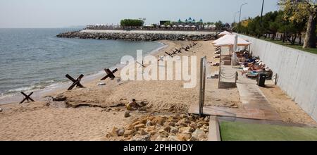 Odessa, Ucraina -2022: Barriere militari metalliche, ricci anticarro sulla spiaggia della città di mare. I vacanzieri si abbronzano accanto ai ricci anticarro in ferro. Recinzioni f Foto Stock