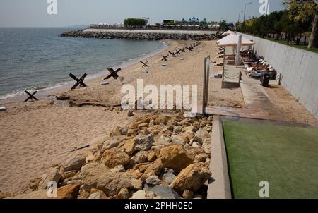 Odessa, Ucraina -2022: Barriere militari metalliche, ricci anticarro sulla spiaggia della città di mare. I vacanzieri si abbronzano accanto ai ricci anticarro in ferro. Recinzioni f Foto Stock