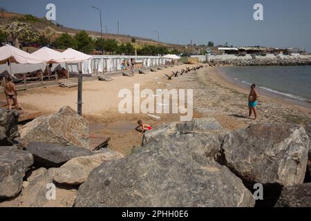 Odessa, Ucraina -2022: Barriere militari metalliche, ricci anticarro sulla spiaggia della città di mare. I vacanzieri si abbronzano accanto ai ricci anticarro in ferro. Recinzioni f Foto Stock