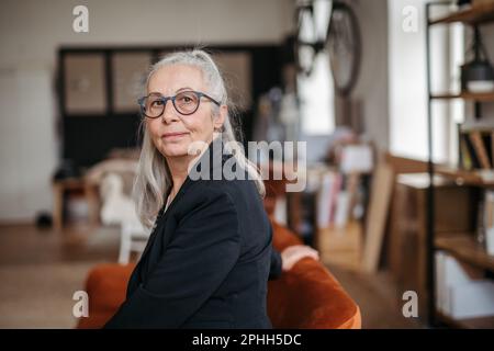 Ritratto di donna anziana penitente seduta in casa. Foto Stock