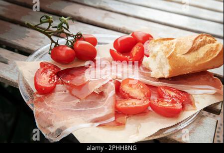 Il prosciutto di Parma, i pomodori e un pezzo di baguette. Parma è un luogo popolare di turismo gastronomico in Italia. Foto Stock