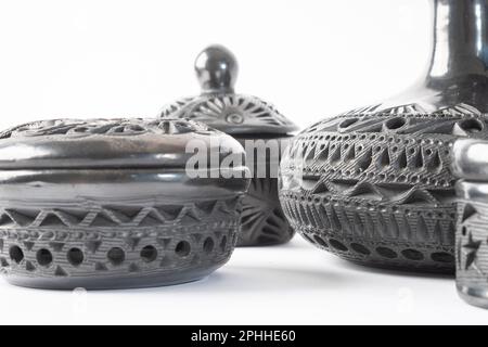 Artigianato tipico messicano. Primo piano, evidenziando la texture di un set di vasi in argilla nera realizzati a mano a Oaxaca, Messico. Sfondo bianco. Foto Stock