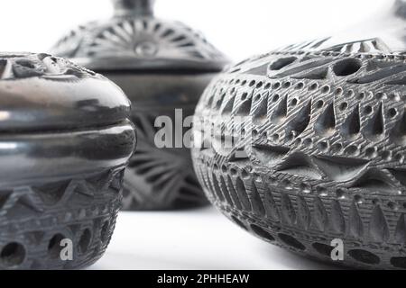 Artigianato tipico messicano. Primo piano, evidenziando la texture di un set di vasi in argilla nera realizzati a mano a Oaxaca, Messico. Sfondo bianco. Foto Stock