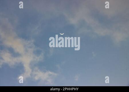 Piccola luna crescente ambientata in un cielo blu. Foto Stock