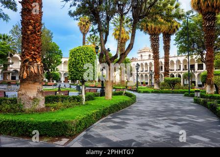 Areqiupa, Perù, vista della piazza principale della città Plaza de Armas e gli edifici coloniali con arcate nascoste nella vegetazione lussureggiante Foto Stock