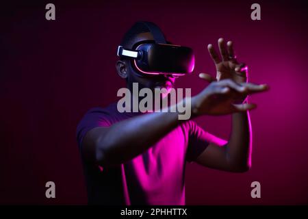 Uomo africano in occhiali vr, che gioca a videogame con visore per realtà virtuale Foto Stock