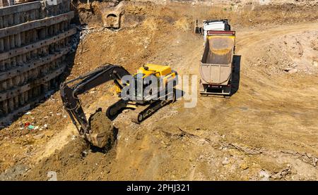 Escavatore e autocarro che lavorano nel settore edile, caricando su autocarro Foto Stock