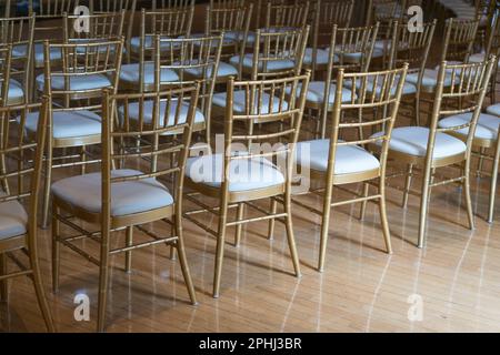 eleganti sedie per banchetti disposte per il pubblico o sedie vuote in una sala con pavimenti in legno Foto Stock