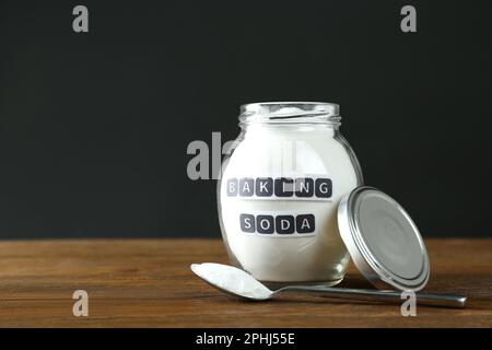 Vasetto e cucchiaio con bicarbonato su tavolo di legno. Spazio per il testo Foto Stock