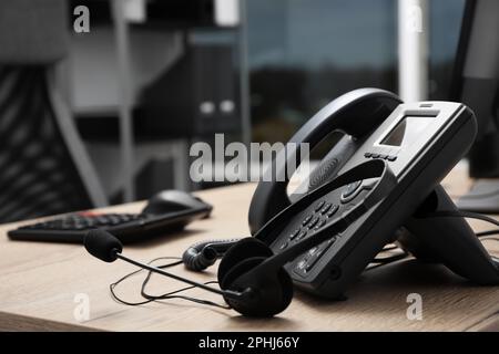 Telefono fisso e cuffie su scrivania in legno interna. Servizio hotline Foto Stock