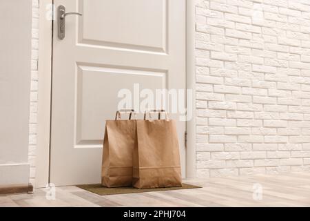 Sacchetti di carta sul tappetino della porta vicino all'ingresso all'interno Foto Stock