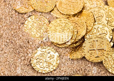 Monete d'oro sepolte del tesoro dei pirati nella sabbia su una spiaggia Foto Stock