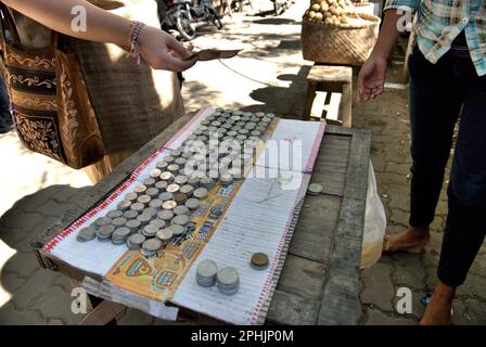 Un venditore di monete, un'offerta comune in pellegrinaggio secondo la tradizione locale, presso il complesso della Grande Moschea di Banten, un patrimonio culturale del periodo del Sultanato di Banten situato in un'area ora chiamata Banten lama (Old Banten) a Serang, Banten, Indonesia, in questa foto scattata nel 2010. "La sostenibilità del patrimonio culturale è fortemente legata all'effettiva partecipazione delle comunità locali alla conservazione e alla gestione di queste risorse", secondo un team di scienziati guidato da Sunday Oladipo Oladeji nel loro articolo di ricerca pubblicato su Sage Journals nell'ottobre 2022. Foto Stock