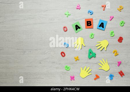 Composizione di posa piatta con abbreviazione ABA (Applied Behavior Analysis) e numeri colorati su tavola di legno bianca, spazio per testo Foto Stock