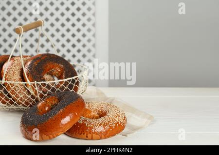 Molti deliziosi bagel freschi su un tavolo di legno bianco, spazio per il testo Foto Stock