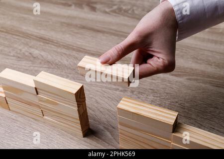 Donna costruzione ponte con blocchi di legno a tavola, closeup. Connessione, relazioni e concetto di trattativa Foto Stock