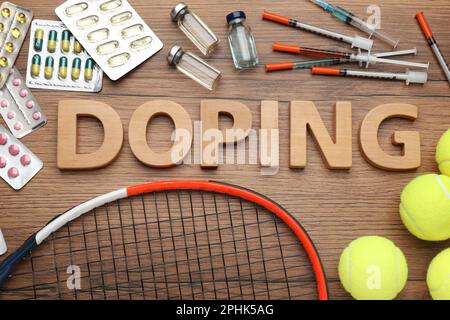 Composizione piatta con doping parola, palle da tennis e droghe su tavolo di legno Foto Stock