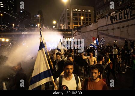 Israele. 23rd Mar, 2023. I manifestanti anti anti delle riforme detengono la bandiera israeliana mentre un cannone d'acqua della polizia spruzza la folla sull'autostrada bloccata di Ayalon, durante una manifestazione anti-riforma a Tel Aviv. Oltre 230.000 persone protestano a Tel Aviv contro il governo di estrema destra di Netanyahu e la sua controversa riforma legale. Mar 25th 2023. (Foto di Matan Golan/Sipa USA). Credit: Sipa USA/Alamy Live News Foto Stock