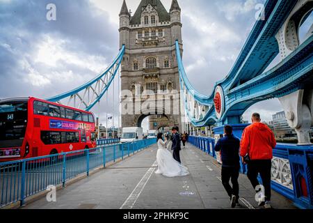 Una coppia in abito nuziale sul Tower Bridge di Londra, in un giorno di blustery, sposa e sposo di Londra sul Tower Bridge, matrimonio, sposarsi Foto Stock