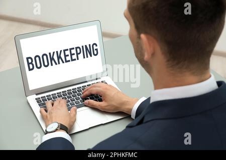 Concetto di contabilità. Uomo che lavora con un computer portatile al tavolo grigio, primo piano Foto Stock