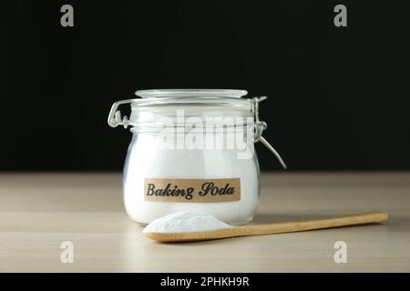 Vasetto e cucchiaio con bicarbonato su tavolo di legno Foto Stock