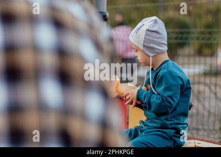 Un ragazzo, persona con sindrome di Down cammina nel parco con la madre Foto Stock