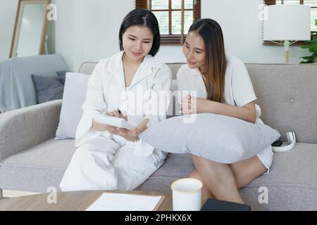 Ritratto di giovane agente asiatico che offre assicurazione sulla vita al cliente utilizzando documento, calcolatrice e tablet nella presentazione del prodotto Foto Stock