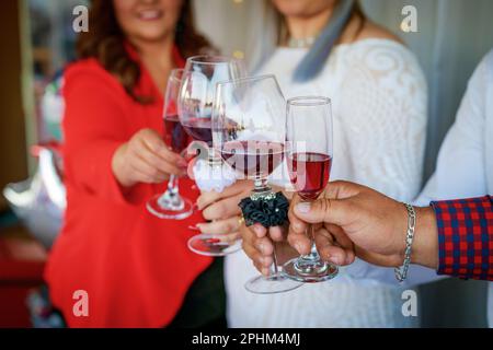 Un gruppo di persone che alzano i propri bicchieri di vino in un brindisi Foto Stock