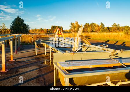 Un posto per lavare i tappeti in Finlandia al tramonto. Un cartello, condizioni scivolose in lingua finlandese nel luogo di pulizia dei tappeti al tramonto . Segnale di avvertenza di Foto Stock